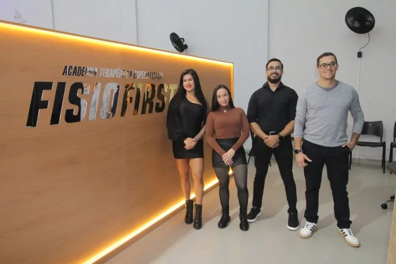 Equipe multidisciplinar Fisio First em frente ao letreiro da academia